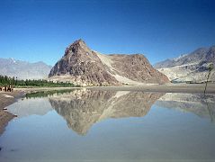 
The Khardong Hill with the Kharpocho Fort is beautifully reflected in the calm Indus River in Skardu (2286m). Skardu is the district headquarters of Baltistan, situated on the banks of the mighty Indus River, just 8 km (5 miles) above its confluence with the Shigar River. The Indus barely seems to move across the immense, flat Skardu valley, 40km long, 10 km wide and carpeted with sand dunes. There are several beautiful blue lakes nearby, including Satpara, and Upper and Lower Kachura.
